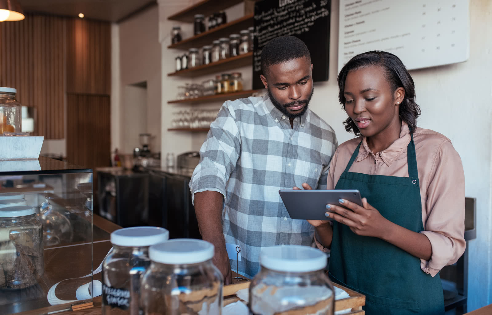 Two business partners use tablet to plan Small Business Saturday ideas for their cafe