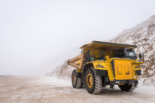 Yellow mining truck drives down snowy road