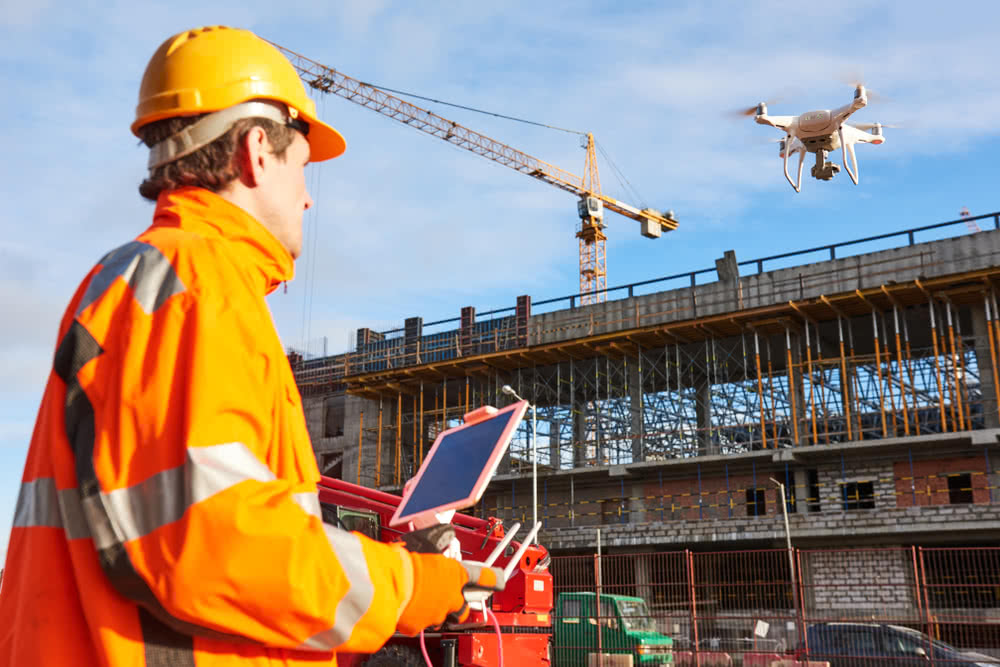 A construction business owner operates a drone on building site, a type of construction technology