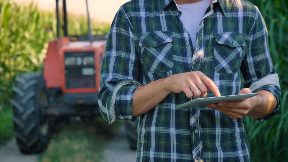 A farmer researches commercial loans on tablet as a way to purchase new equipment 