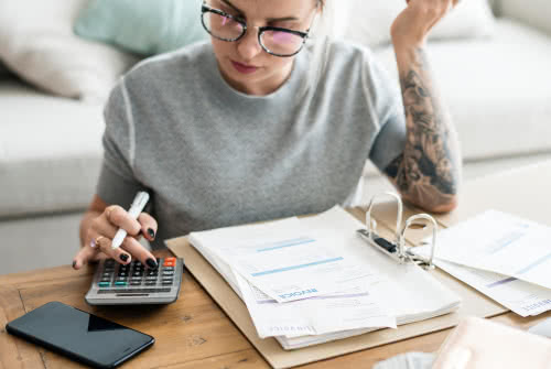 Female business owner pays bills at her coffee table