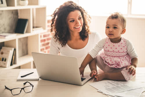 A mother sits with her baby at a desk 