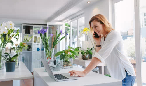 Female florist standing at her flower shop takes orders for Amazon Prime day