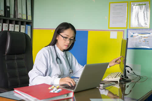 Health clinic owner keeps track of employee hours on laptop