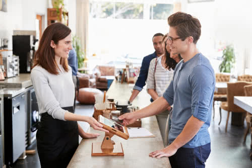 Coffee shop barista at a counter fosters customer loyalty, part of a business contingency plan