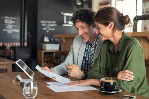 Two business owners review paperwork at a cafe