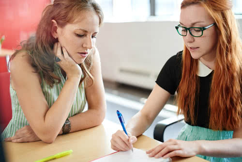 Two women business owners work on a project together around a table