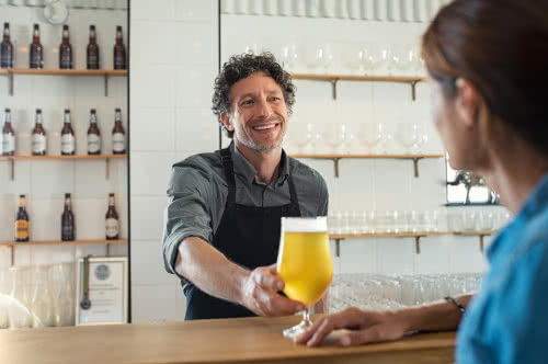 Bartender serves beer to customer, following his bar business plan