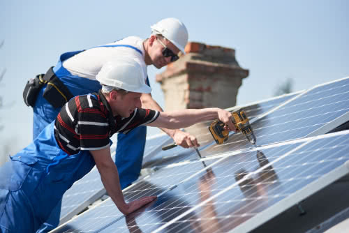 Construction workers with green business certification install solar panels