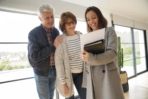 Senior couple with real estate agent visiting contemporary house