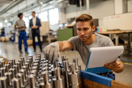 Male factory worker restocks inventory bought with working capital 