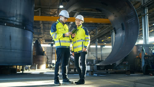 Two engineers stand in front of a new warehouse funded with small business venture capital