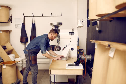 Man in workshop follows small business IT security rules on his laptop 