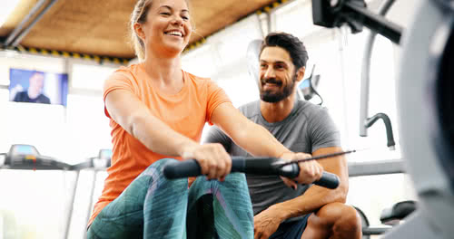Woman works with personal trainer on new equipment at the gym