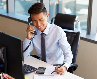 Business owner making phone call sitting at desk in office