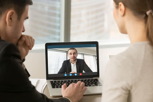 Two remote workers on a video call with a coworker