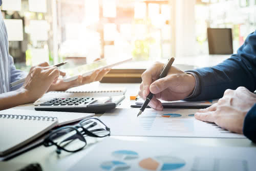 Close-up of two people calculating the cost of small business health insurance options