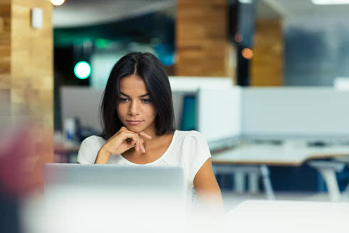 A businesswoman looks thoughtfully at her laptop, protected by cybersecurity for small business